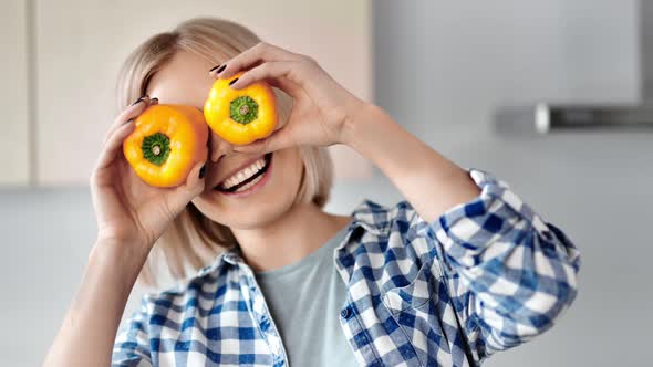 Portrait of Playful Young Woman Smiling Covering Eyes By Yellow Pepper Medium Closeup