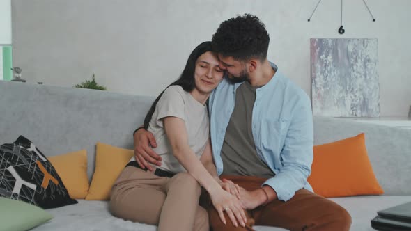 Young Married Couple Sitting On Sofa At Home