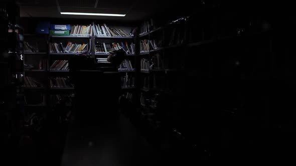 Fluorescent Lights illuminating an Empty Room with many Books.