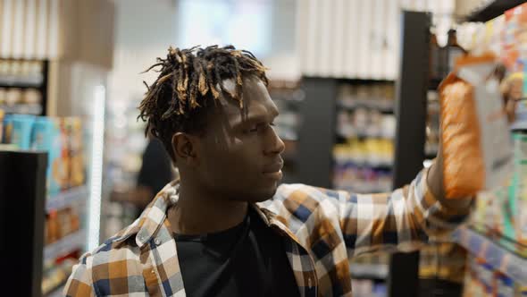 Handsome African American Guy Chooses Corn Flakes in the Grocery Store