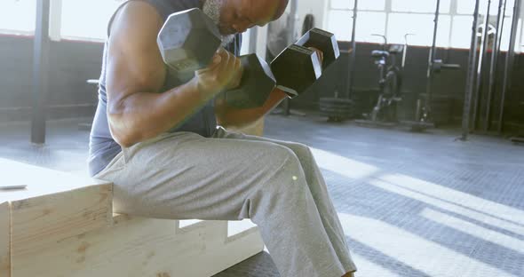 Senior man exercising with dumbbell in the fitness studio