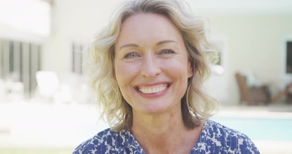 Portrait of smiling caucasian woman looking at camera by pool