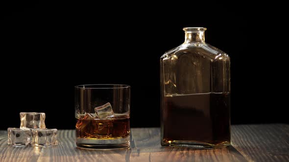 Pouring Whiskey, Cognac Into Glass. Black Background. Pour of Alcohol Drink