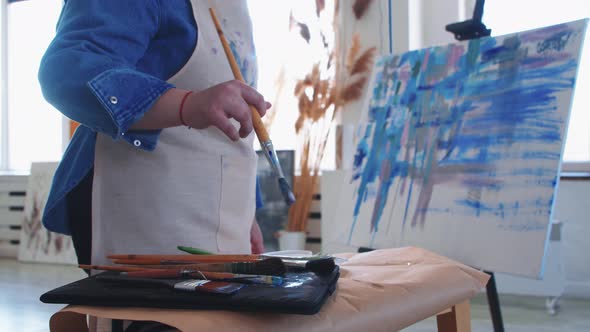 A Woman Paint Artist Taking a Brush and Drawing a Colorful Painting on a Canvas