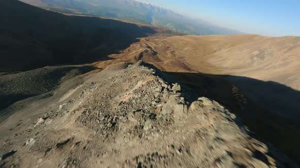 FPV Sport Drone Flight Dive Over Natural Mountain Ridge Stone Structure Sunlight Glare