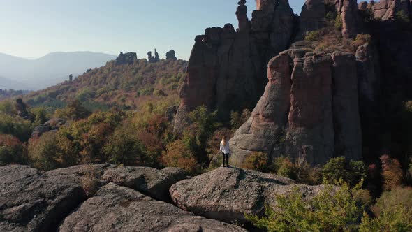 Aerial video with a woman at the edge of stunning rock formation