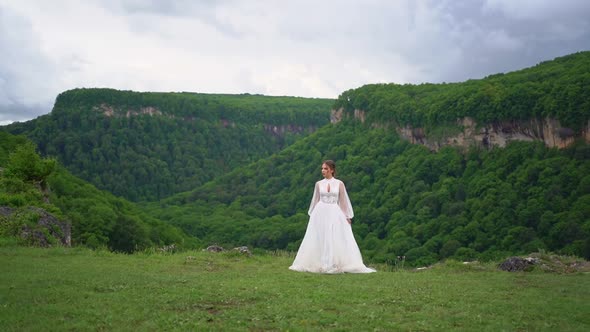 A Woman in a Wedding Dress and Black Boots Dances in the Mountains