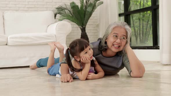 Asian Grandmother and Granddaughter lying on the floor in the living room