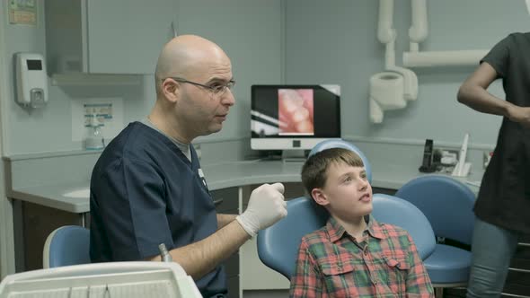 Dentist and dental assistant preparing dental treatment for boy