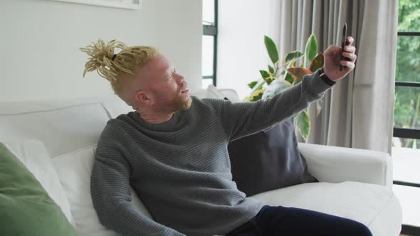 Albino african american man with dreadlocks using smartphone