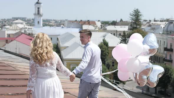 Couple with balloons walking on a roof