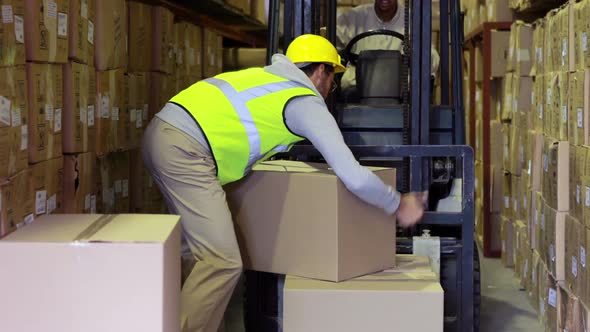 Warehouse Worker Packing Boxes on Forklift