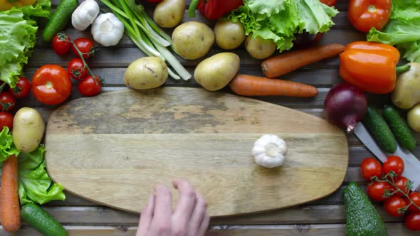 Male Hands Sliding Garlic Bulb on Wooden Cutting Board