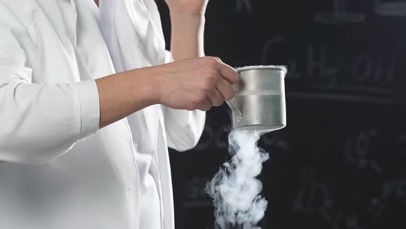 Chemical Show Using Liquid Nitrogen a Thick White Vapor Coming Out of a Glass Held in the Hands of a