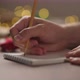 Slow Motion Orbit Shot Man Writes Christmas Gifts Notepad Pencil Under Warm Light Evening - VideoHive Item for Sale