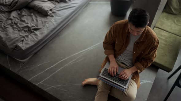 Overhead view of Asian man wearing casual cloth working on laptop