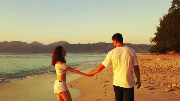 Romantic couple sunbathing on paradise coast beach trip by blue lagoon and white sandy background of