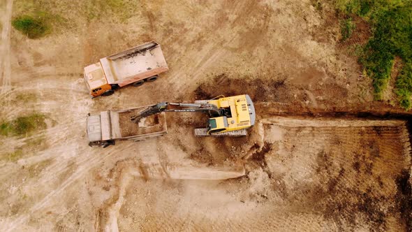 Excavator loading dump truck tipper at excavation site.