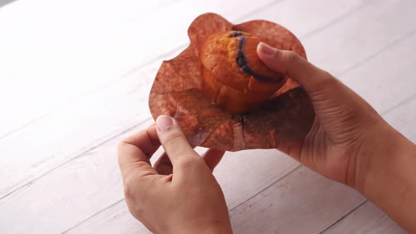 Rear View of Women Hand Holding Muffin Cake on Table