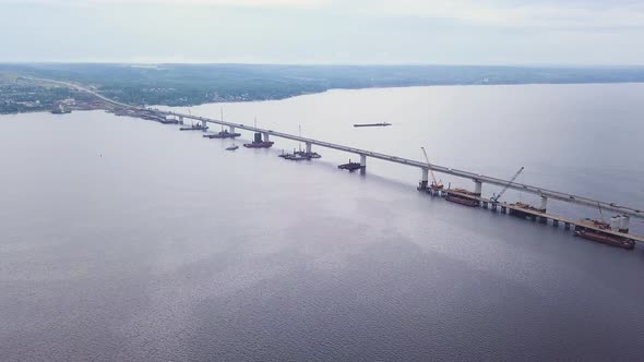 Aerial View of a Wide Calm River Crossed By the Narrow Bridge with Driving Cars