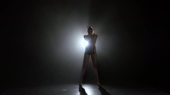 Girl Gymnast with Mace in Hand Revolve Around Him. Black Background. Light Rear. Silhouette