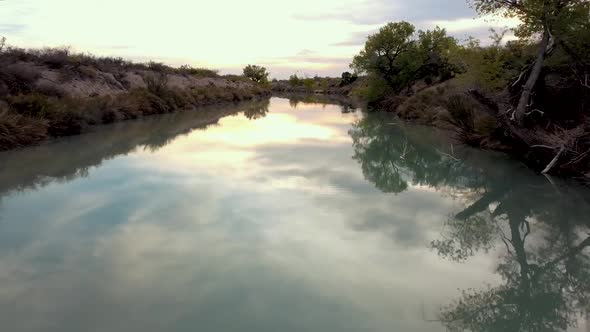 Aerial footage drone over blue water in a creek.