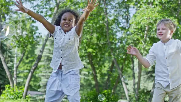 Happy Little Friends Playing with Soap Bubbles in Park alt