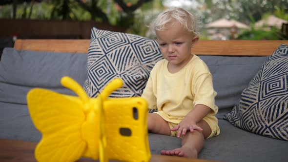 Toddler Child Watching a Cartoon on a Digital Tabled in a Kid Riendly Yellow Butterfly Case