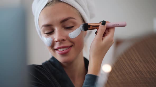 Handsome woman with a towel on her head doing makeup