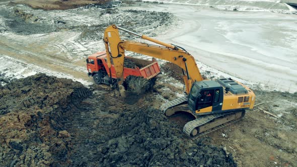 Excavator Loads a Truck While Working at a Quarry