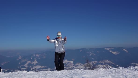 Young Woman Is Jumping at the Top of Mountain with Beautiful View Powerful Snowy Mountains and Blue