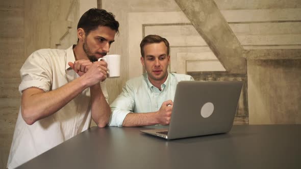 Two Young Man in the Coffee House Looking on the Screen Computer and Talking