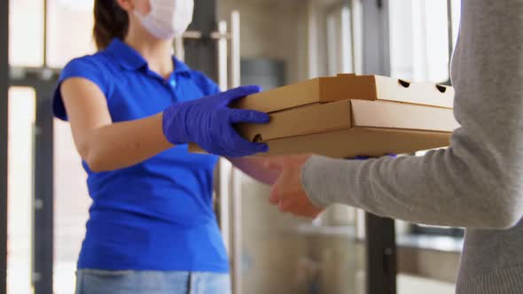 Delivery Girl in Mask Giving Pizza Boxes To Woman