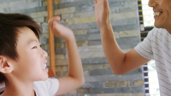 Father and son giving high five to each other in bathroom