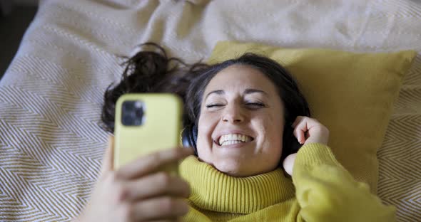 Authentic shot of woman on the bed listening to music and singing