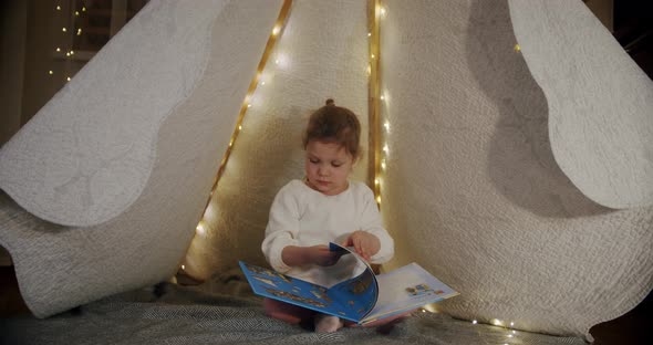 Child in a Wigwam Tent Play at Night and Read a Book