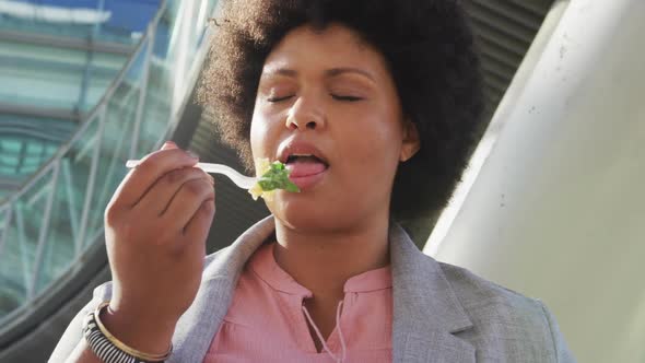 Plus size biracial woman eating salad in city