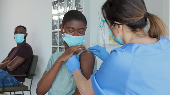 Female doctor giving injection to black female patient