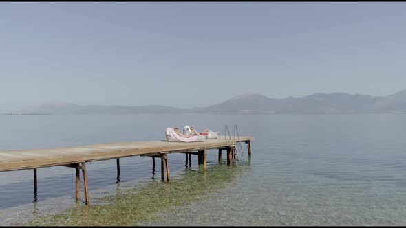 Aerial view passing by two attractive woman sunbathing in Panagopoula, Greece.