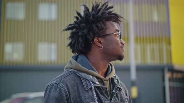 Portrait of African American Man with Dreadlocks in Eyeglasses Turning To Camera Smiling