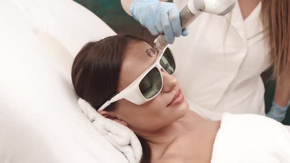 Beautician Working on Female Forehead with Laser