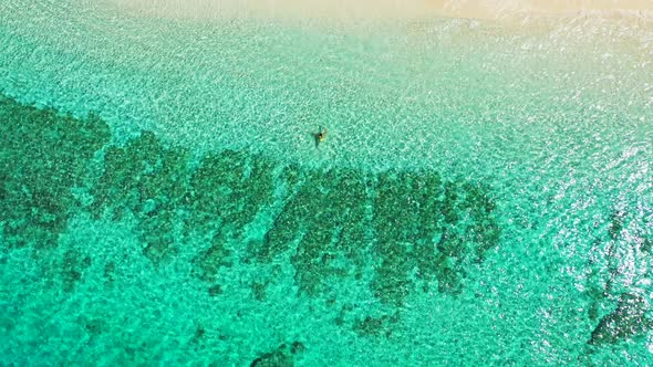 Two female friends swimming in the clear blue waters of a tropical beach island with beautiful coral