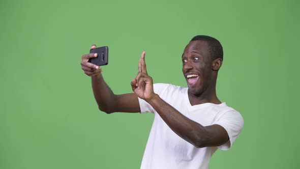 Young African Man Taking Selfie Against Green Background