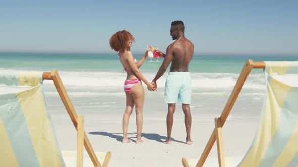 African american couple drinking cocktail seaside