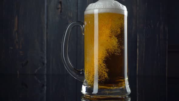 Slow Motion Shot of Beer Pouring Into Beer Mug. White Beer Foam Goes Beyond the Edges of the Mug