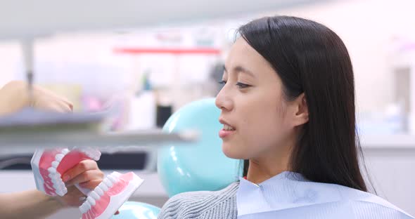 Dentist teaching patient how to brush teeth