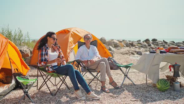 Two Beautiful Relaxed Girlfriends Travelers Enjoying Summer Vacation and Drinking Cold Beer at Hot