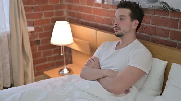 Focused Young Man Sitting and Thinking About Idea in Bed