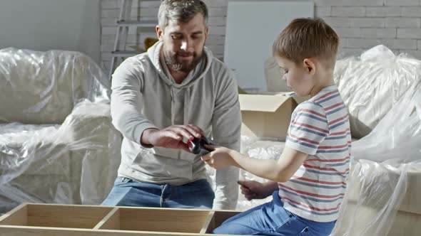 Boy Watching Father Assembling Furniture