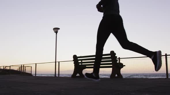 African american man exercising outdoors, running by seaside in the evening